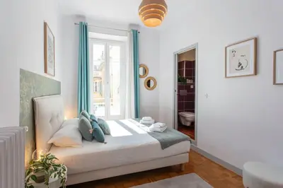 a bedroom with a bed with blue pillows and a window at #57 Suite Notre Dame Central balcony & AC in Nice
