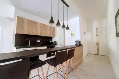 a kitchen with a bar with chairs and a sink at Bright air-conditioned flat in the city centre in Nice