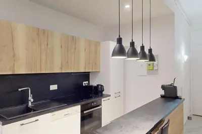 a kitchen with white cabinets and a black counter top at Bright air-conditioned flat in the city centre in Nice