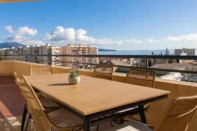 a wooden table and chairs on a balcony with a view at Vue mer sublime, terrasse ensoleillée et parking in Nice