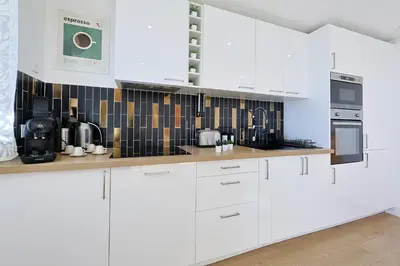 a white kitchen with white cabinets and appliances at Vue mer sublime, terrasse ensoleillée et parking in Nice