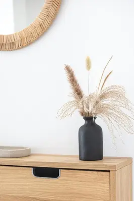 a black vase with feathers in it sitting on a table at Vue mer sublime, terrasse ensoleillée et parking in Nice