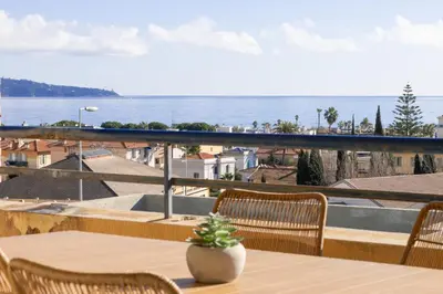 a table and chairs on a balcony with a view of the ocean at Vue mer sublime, terrasse ensoleillée et parking in Nice