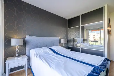a bedroom with a bed and a wall with a mirror at Superbe 2 pièces Clim et Parking in Nice