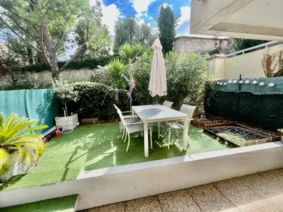 a small garden with a table and chairs on grass at Le Rieviera Bay-Parking-Jardin Pick up Airport in Saint-Laurent-du-Var