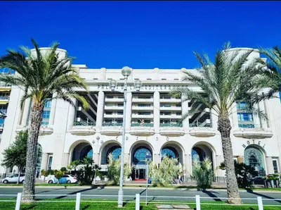 a building with palm trees in front of it at Le Grand Palais de la Méditerranée Beach Access Apartments - Top Choice In Nice in Nice