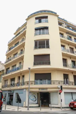 a tall white building with balconies on a street at Cosy 3 pièces à 5 min de la PROM in Nice