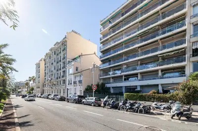 a street with cars parked in front of a large building at Panoramic Sea View - 1 Bdr Promenade des Anglais in Nice