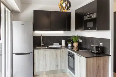 a kitchen with wooden cabinets and a white refrigerator at Le Mimosa - Calm - Spacious - 200m from the sea - Parking in Cagnes-sur-Mer