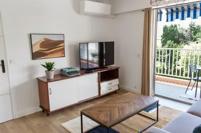a living room with a flat screen tv on a cabinet at Le Mimosa - Calm - Spacious - 200m from the sea - Parking in Cagnes-sur-Mer