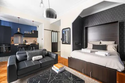a bedroom with a large bed and a black couch at Raffinement en pleine ville in Nice