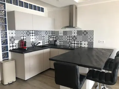 a kitchen with a black counter top and black chairs at Eros in Nice