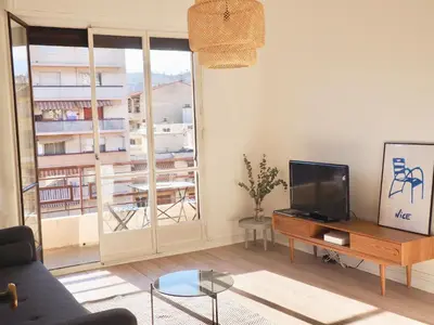 a living room with a tv and a large window at Appartement proche de Libération avec balcon ensoleillé in Nice