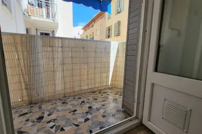 a balcony with a glass door and a tiled floor at Apartment 3 pieces par la mer avec climatisation in Nice