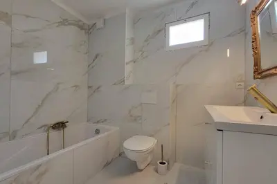 a white bathroom with a toilet and a sink at Apartment 3 pieces par la mer avec climatisation in Nice