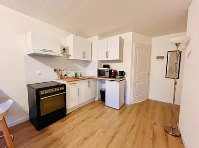 a kitchen with white cabinets and a black stove at City & Serenity - Studio Proche Gare in Nice