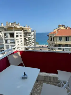 a white table and chairs on a balcony with the ocean at Magnifique 2 pièces à 2 pas de la mer in Nice
