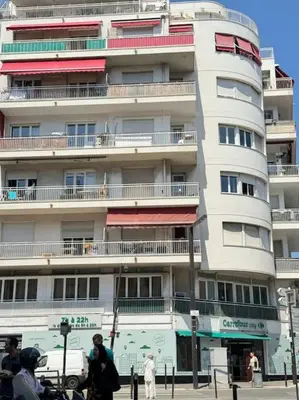 a tall white building with people walking in front of it at Magnifique 2 pièces à 2 pas de la mer in Nice