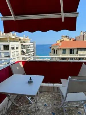 a white table and chairs on a balcony with the ocean at Magnifique 2 pièces à 2 pas de la mer in Nice