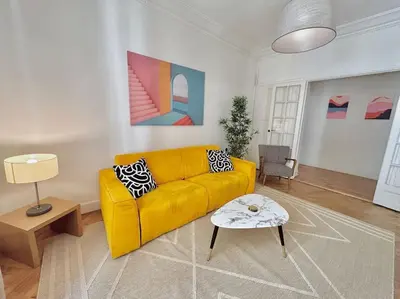 a living room with a yellow couch and a table at Charmant 3P en centre ville, spacieux et calme in Nice