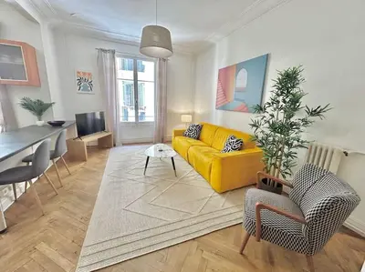 a living room with a yellow couch and a table at Charmant 3P en centre ville, spacieux et calme in Nice
