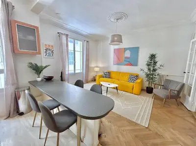 a living room with a table and a yellow couch at Charmant 3P en centre ville, spacieux et calme in Nice