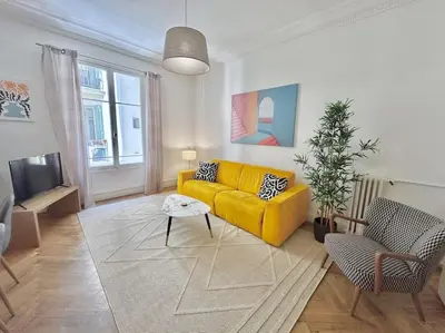 a living room with a yellow couch and a table at Charmant 3P en centre ville, spacieux et calme in Nice