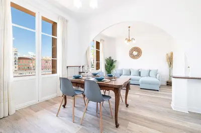 a white living room with a wooden table and chairs at Large Central 2 Bdr & Garage in Nice