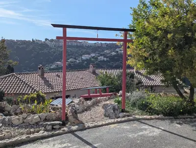 a red pergola with a bench in a garden at Maison L'Aloé in Nice