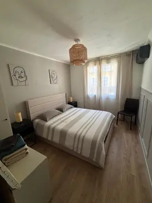 a bedroom with a large bed and a table at Appartement confortable et cosy sur le port de Nice in Nice