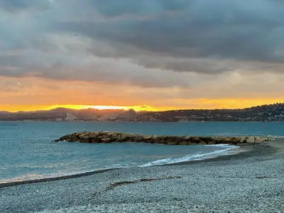 a beach with a rock in the water at sunset at Side Ocean View Studio, 24H Check-In and Out, Air Conditioner, Close to Airport in Cagnes-sur-Mer