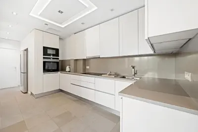 a kitchen with white cabinets and a stainless steel refrigerator at 4 pièces vue mer, 6 pers, balcon, WiFi, garage in Villefranche-sur-Mer