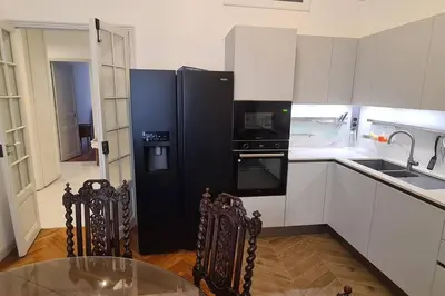 a kitchen with a black refrigerator and a glass table at Superbe 4 pièces 75 m carrés pour 2 à 6 personnes Centre Parking 3 jours minimum in Nice