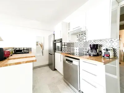 a kitchen with white cabinets and a stainless steel refrigerator at t3 cagnes sur mer in Cagnes-sur-Mer