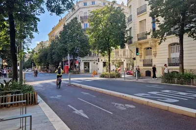 a person riding a bike down a city street at Sunny Escape in Nice