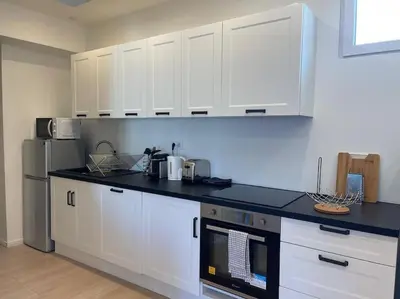 a kitchen with white cabinets and a black counter top at Appartement à 2 pas de la mer et Parking privé in Nice