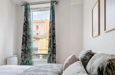 a bedroom with a window with a view of a city at Charming 2-Bedroom Retreat Near City Center with Excellent Transport Links in Nice