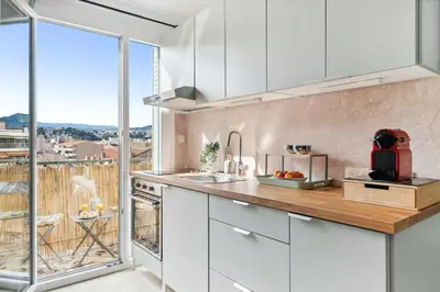 a kitchen with white cabinets and a large window at Vista Nissa - À Quelques Pas du Port in Nice