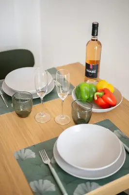a table with plates and wine glasses and a bottle of wine at Vista Nissa - À Quelques Pas du Port in Nice