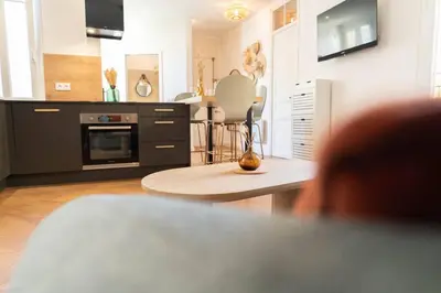 a living room with a table and a kitchen at Superbe appartement deux chambres, centre proche port in Nice