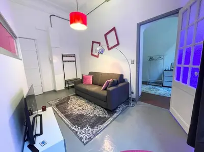 a living room with a couch and a rug at Cosy appartement, moderne, fuchsia, industriel in Nice