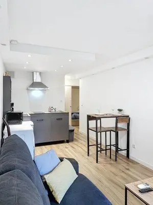 a living room with a blue couch and a kitchen at Studio proche mer - Climatisé in Cagnes-sur-Mer