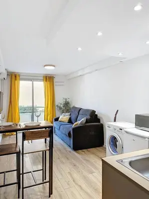 a living room with a blue couch and a kitchen at Studio proche mer - Climatisé in Cagnes-sur-Mer
