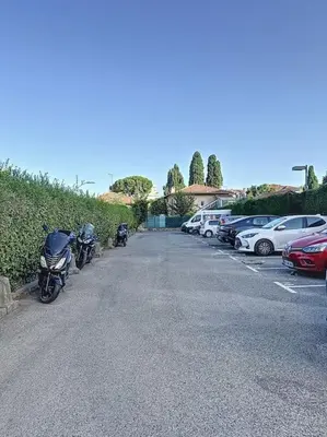 a parking lot with a motorcycle parked next to cars at Studio proche mer - Climatisé in Cagnes-sur-Mer