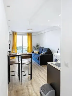 a kitchen and living room with a couch and a table at Studio proche mer - Climatisé in Cagnes-sur-Mer