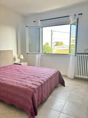 a bedroom with a purple bed and a window at Charmant T3 Rénové Proche Mer, Aéroport et Gare ! in Saint-Laurent-du-Var