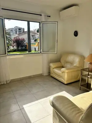 a living room with a couch and a chair and a window at Charmant T3 Rénové Proche Mer, Aéroport et Gare ! in Saint-Laurent-du-Var