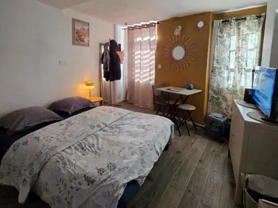 a bedroom with a bed and a desk with a television at Atypique studio en bas du Château in Cagnes-sur-Mer