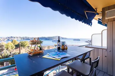 a table on a balcony with a view of the ocean at Esterel AP4431 By Riviera Holiday Homes in Villefranche-sur-Mer