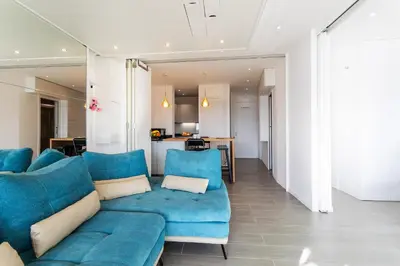 a living room with a blue couch and a kitchen at Esterel AP4431 By Riviera Holiday Homes in Villefranche-sur-Mer